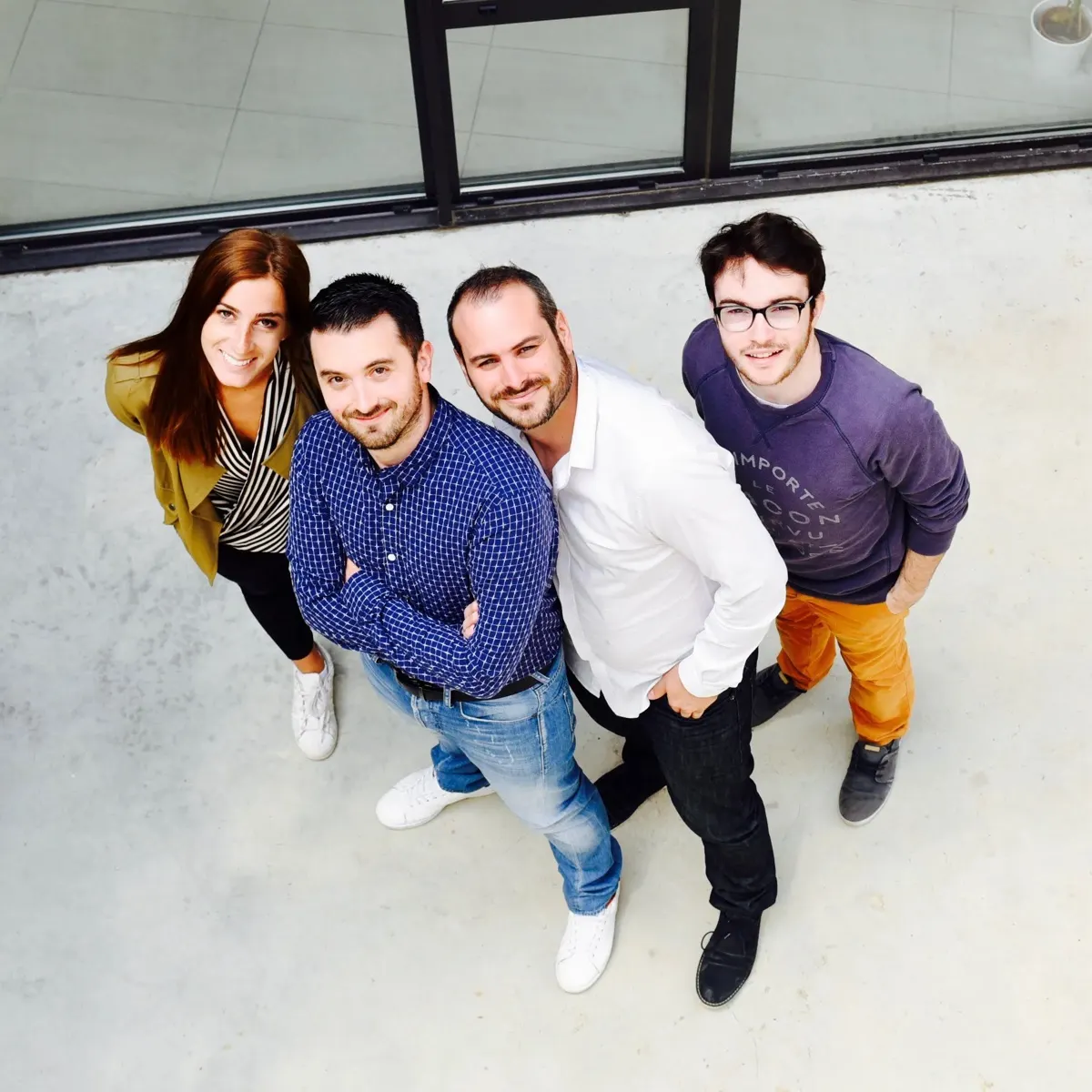 The Dev-id team gathered and smiling in front of the office windows